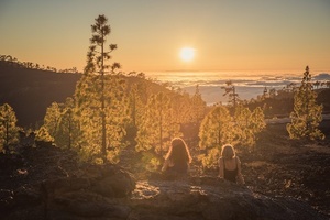 zwei Frauen sitzen in den Canadas von Teneriffa und schauen den Sonnenuntergang an